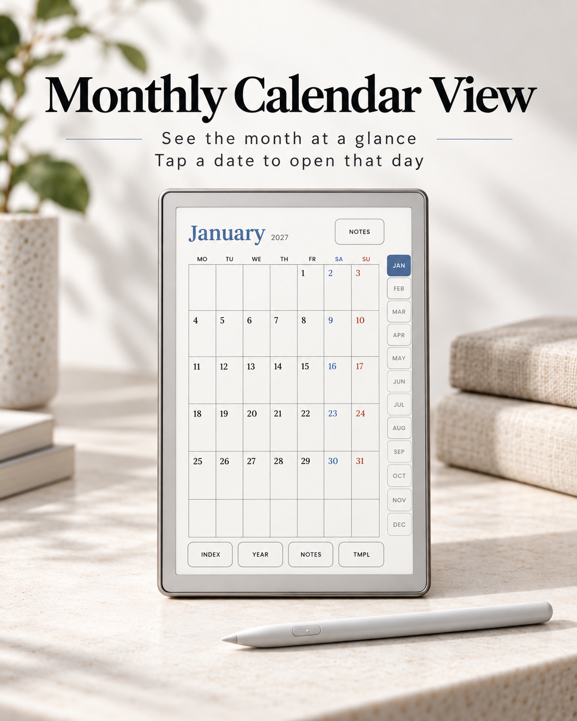 A digital tablet on a light stone surface displays a monthly calendar view for January 2027, with text above reading 'Monthly Calendar View' and a stylus in front. The scene is styled with books, a plant, and stacked neutral-toned boxes in soft natural light.